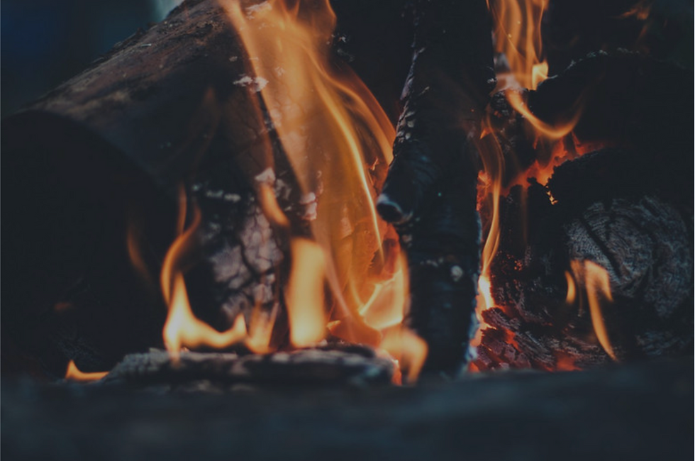 Flames burning brightly in a cozy campfire with wood logs in dim light